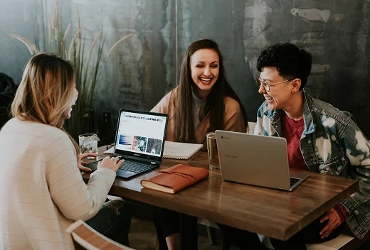 A male and two female employees happy while collaborating together.