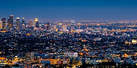 Blue scenery of a city with sky scrappers lit up with lights.